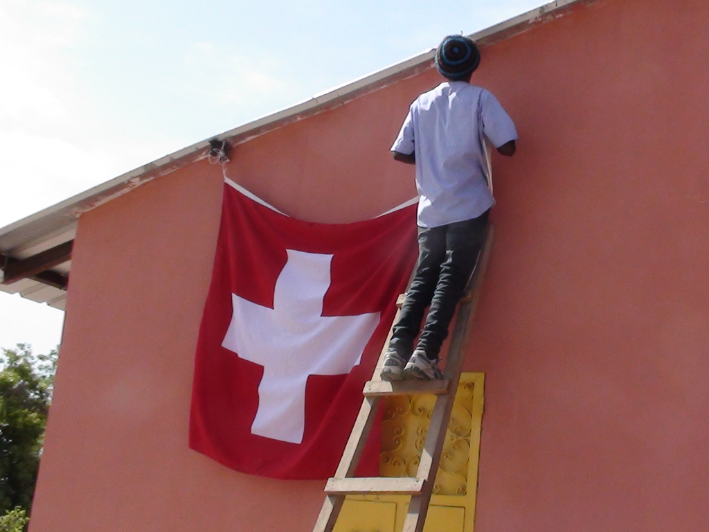 Elhadji hängt Schweizer Fahne auf